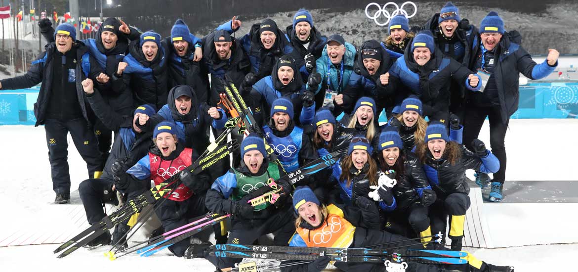 Ett stort gäng som jublar med skidor framför sig. 