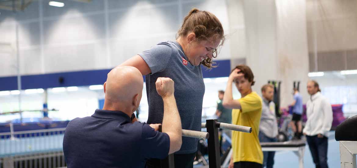 Jesper Sjökvist i SOK:s resursteam assisterar skidskytten Elvira Öberg under fystesterna på Bosön. Foto: SOK