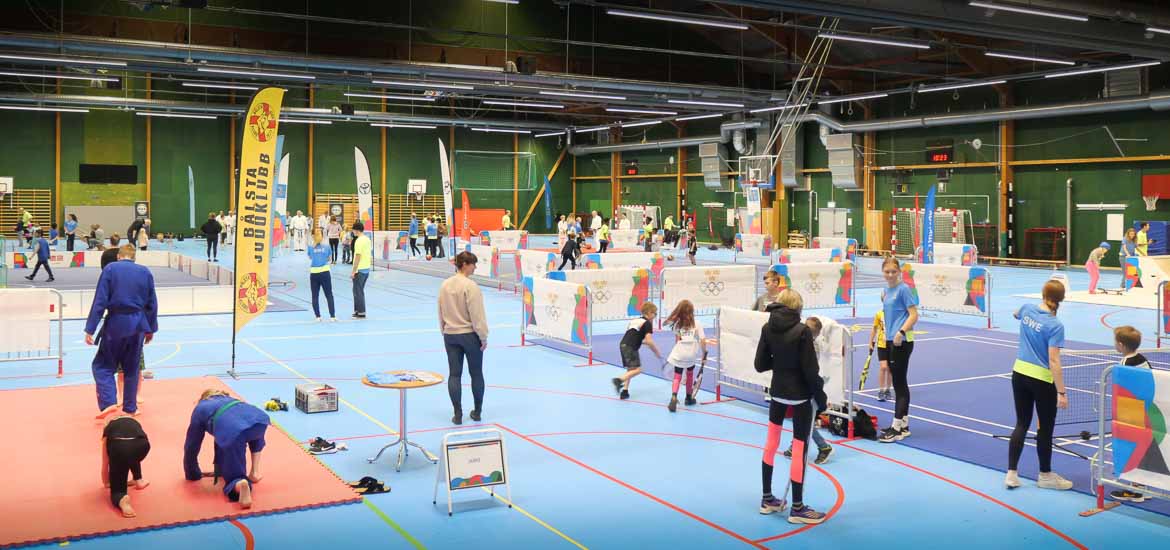 Idrottshall full med barn som provar på idrott. 