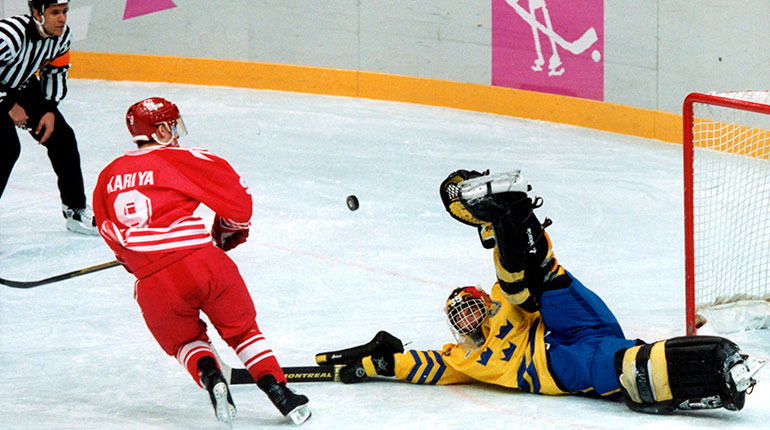 Hockeymålvakt som sträcker upp benet högt i luften och hindrar en puck från att flyga in i mål. 